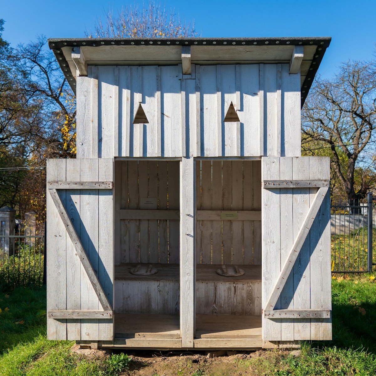 a wooden outhouse with two doors open